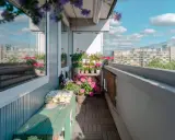 Uroczy balkon z drewnianą podłogą, zieloną ławką i mnóstwem kwiatów. Idealne miejsce, by odpocząć, gdy szukasz pomysłów, co na balkon zamiast płytek.