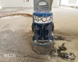 Maszyna APCON przygotowuje podłoże pod parkiet, szlifując beton. Wąż odkurzacza leży obok.