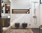 Nowoczesna, wąska łazienka z prysznicem. W centrum uwagę przyciąga ściana z terazzo, a obok niej wiszące toalety i bidet.