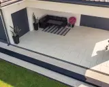 Nowoczesny taras z jasnej kostki brukowej, z wygodnym narożnikiem i grillem.