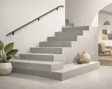 Nowoczesne schody z betonu architektonicznego, czyli co to jest mikrocement. Obok donica z rośliną i wazony.