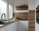 Mała kuchnia inspiracje: białe szafki, drewniany blat i płytki, czarny zlew, ozdoby na półce.