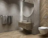 Nowoczesna łazienka szara z drewnem. Betonowe ściany, drewniana podłoga w jodełkę, wisząca szafka z umywalką i okrągłe lustro.