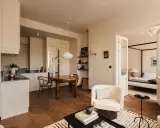 Jak urządzić salon? Jasne, przytulne wnętrze z aneksem kuchennym, jadalnią i sypialnią. Drewniana podłoga w jodełkę, wygodne fotele i stylowe dodatki.