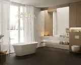 Elegancka łazienka z wolnostojącą wanną i zabudową nad geberitem.
