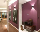 Nowoczesny przedpokój w bloku inspiracje: fioletowe ściany, drewniana podłoga, grafiki i stylowe oświetlenie tworzą elegancką przestrzeń.
