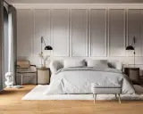 Elegancka ściana w sypialni z ozdobnymi panelami, łóżko z szarą pościelą, rattanowe meble i stylowe lampki nocne tworzą przytulną atmosferę.