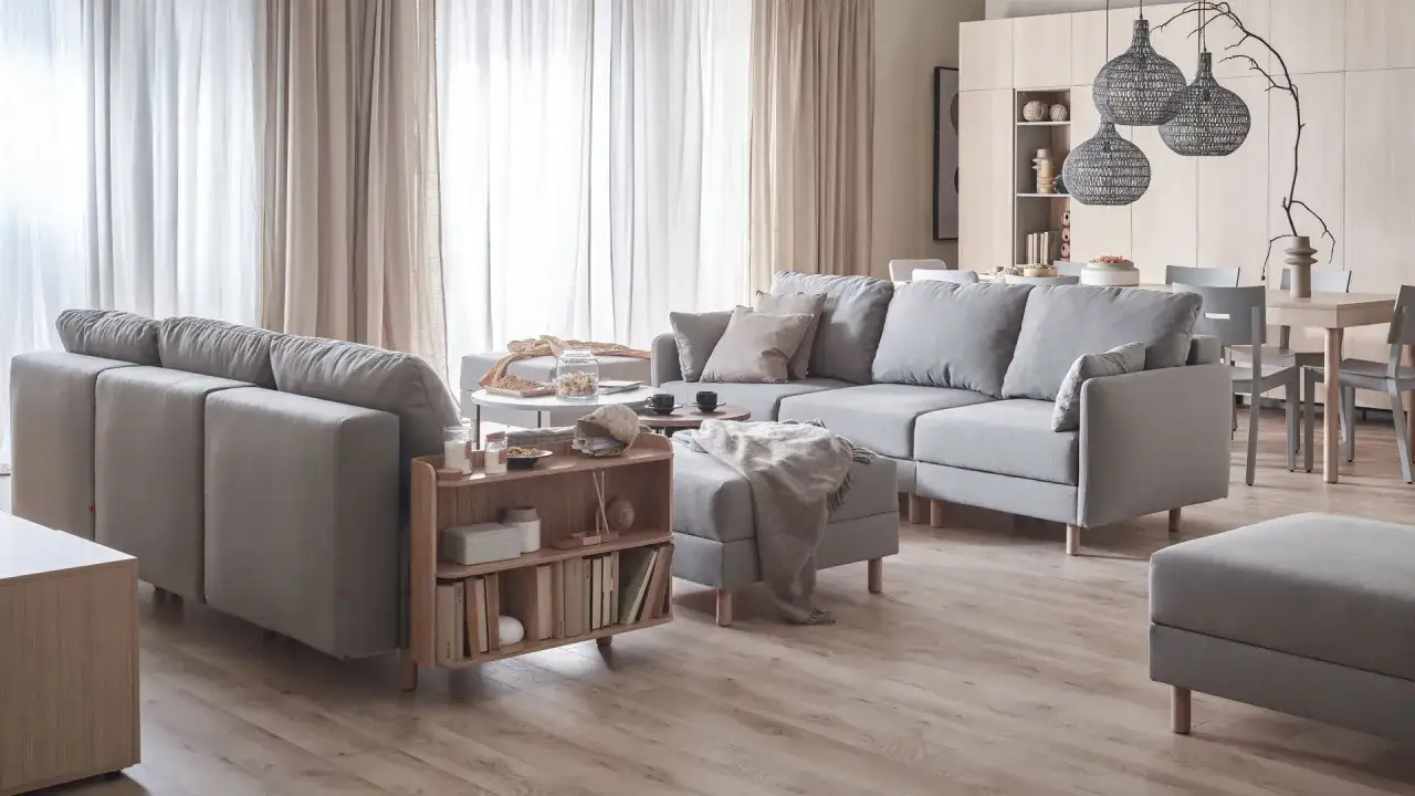Przytulny salon inspiracje: szare sofy, drewniane meble, jasne zasłony i dekoracje tworzą ciepłą atmosferę.