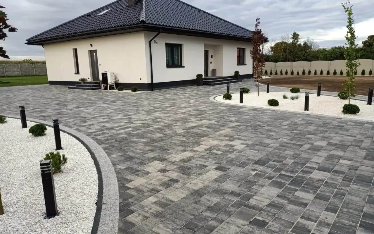 Nowoczesne projekty kostki brukowej wokół domu tworzą elegancką ścieżkę i podjazd.