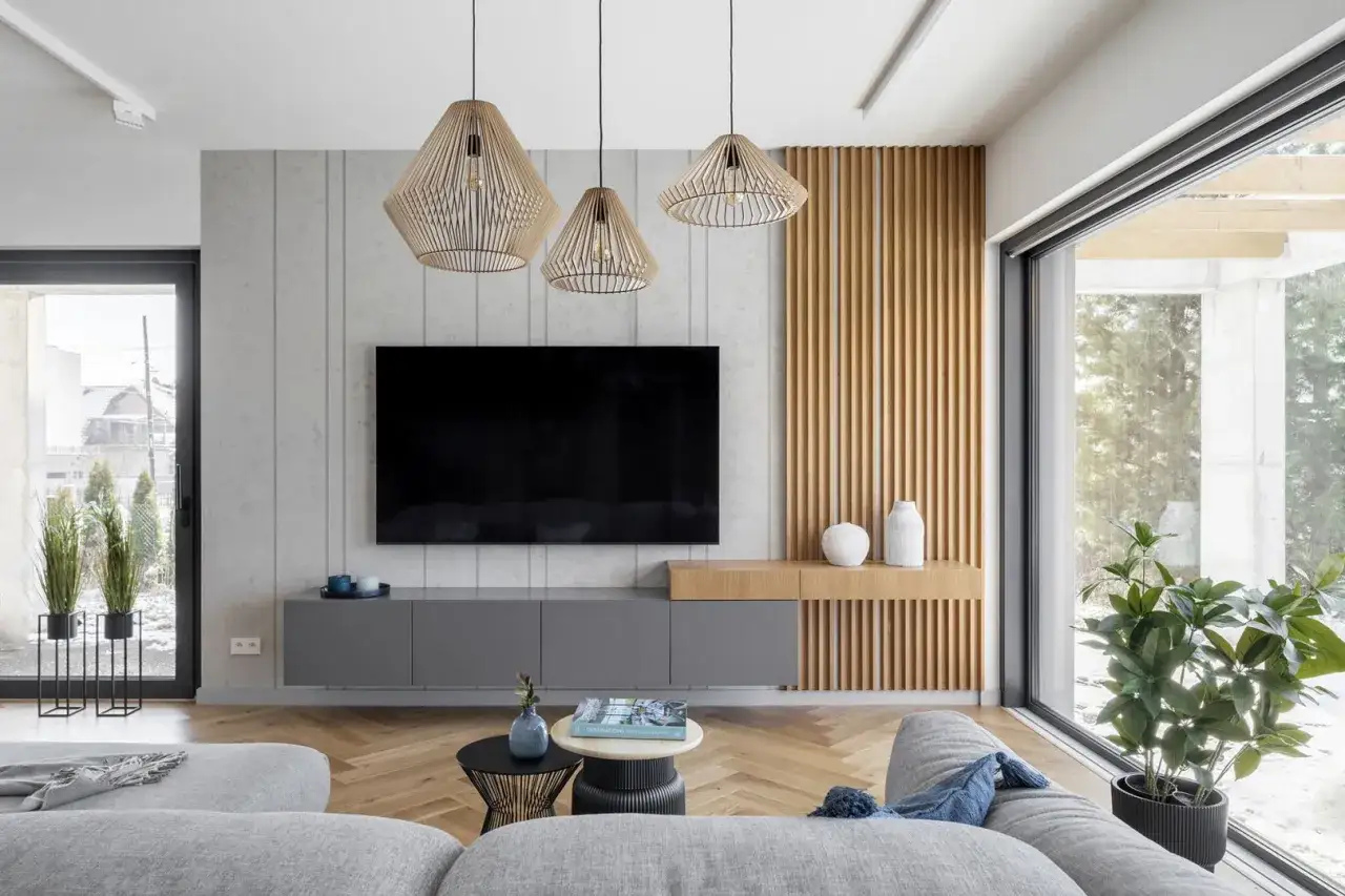 Nowoczesne dekoracje do salonu inspiracje: szare meble, drewniane panele, ażurowe lampy i duża sofa tworzą przytulną przestrzeń.