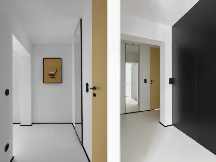 Minimalistyczny, mały przedpokój inspiracje ściany: złote i czarne drzwi, lustro, grafika z fotelem Eamesa.